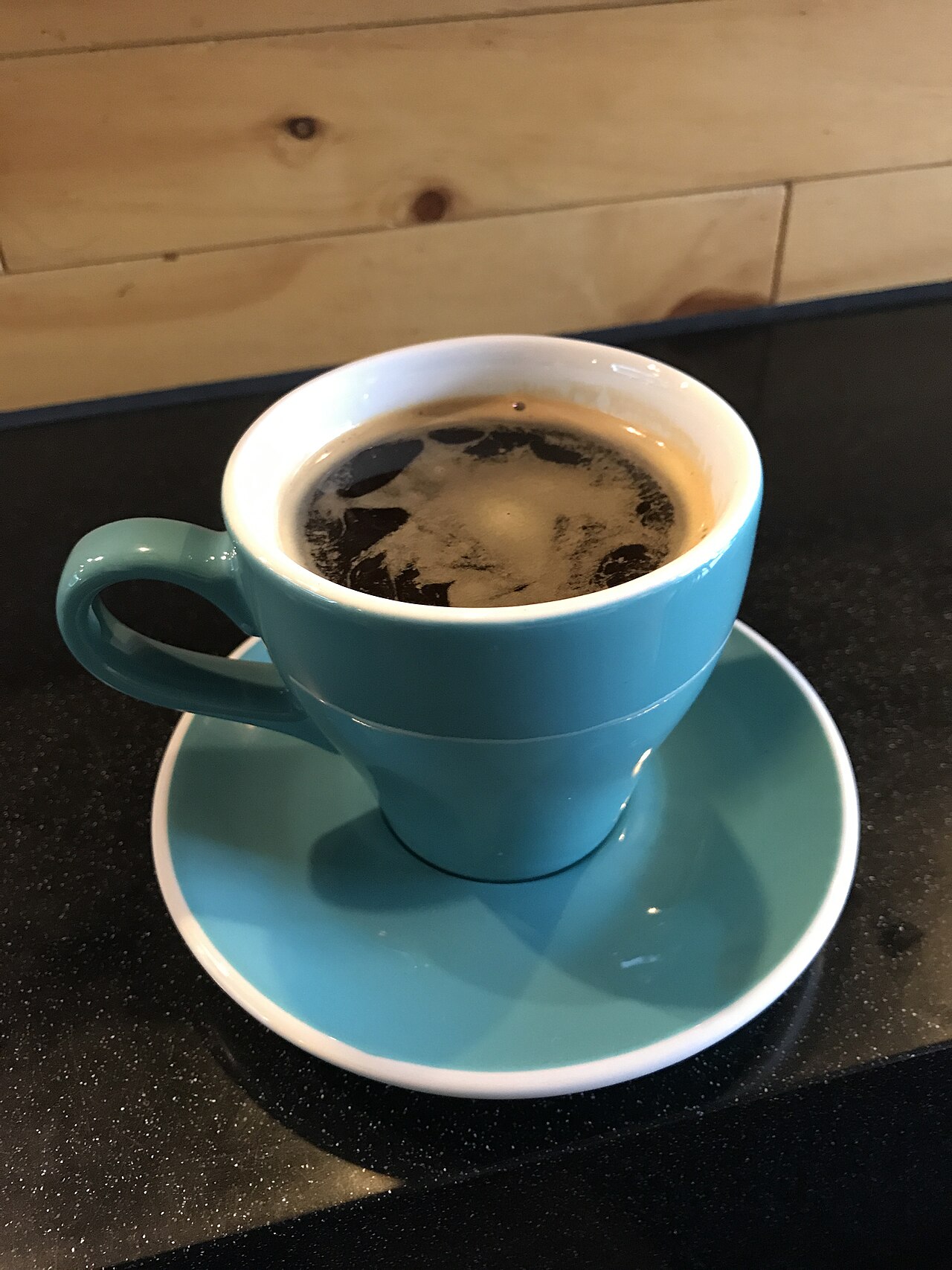 A long black americano with crema in a teal cup