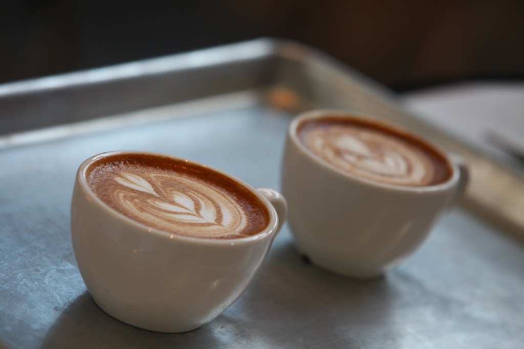 Two cappuccinos with latte art on a metal tray