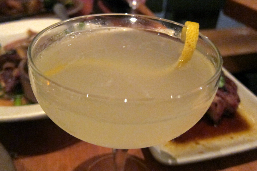 A pale lemon cocktail in a coupe with a twist