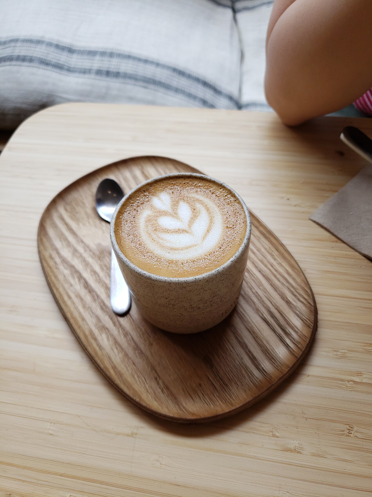 A cortado with tulip latte art on a wooden tray