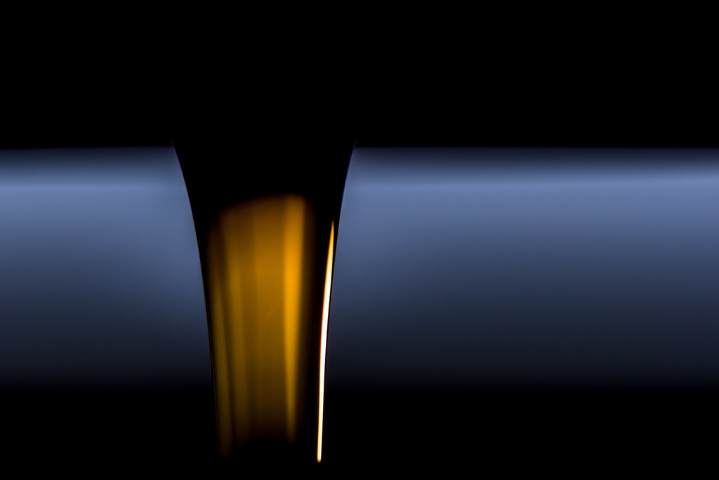A dark stream of coffee pouring against a black background