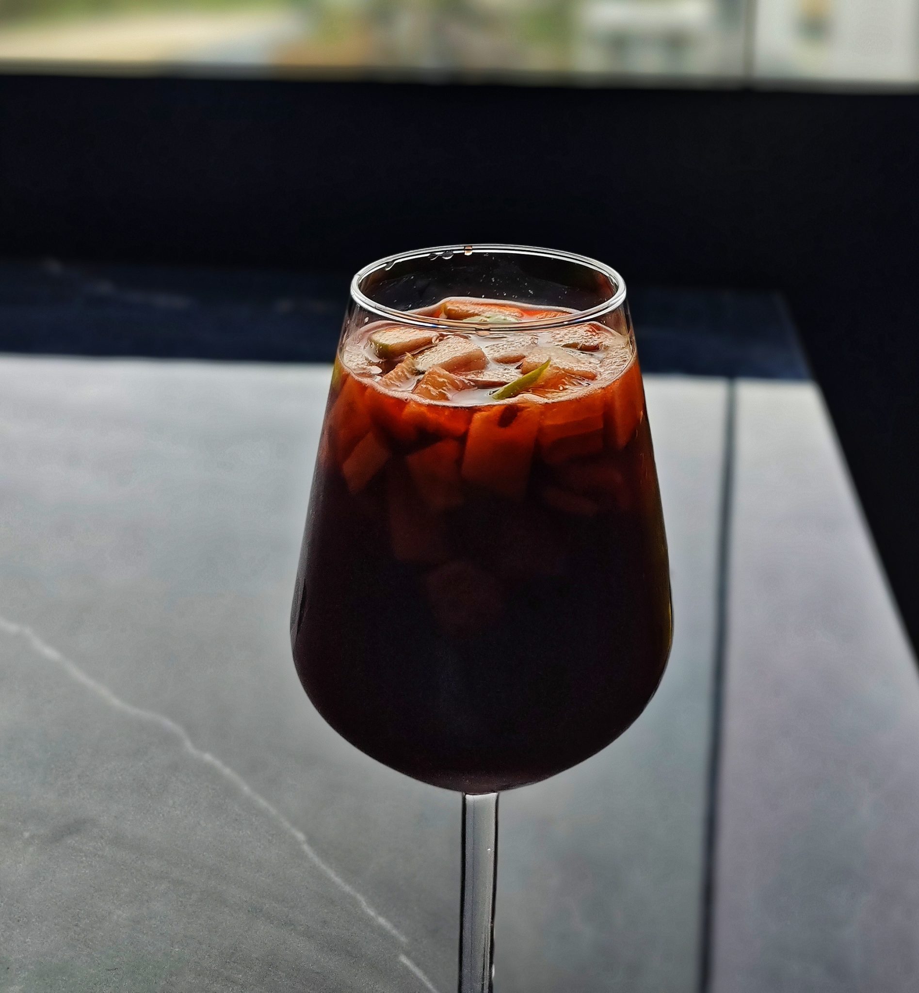 A dark sparkling drink in a stemmed glass