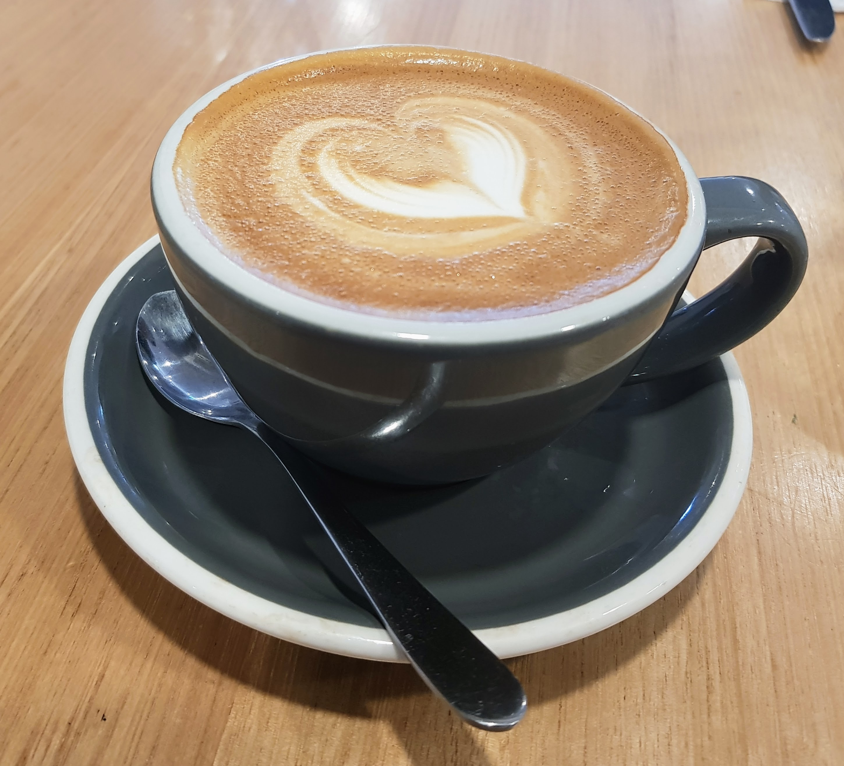 A latte with heart latte art in a gray cup