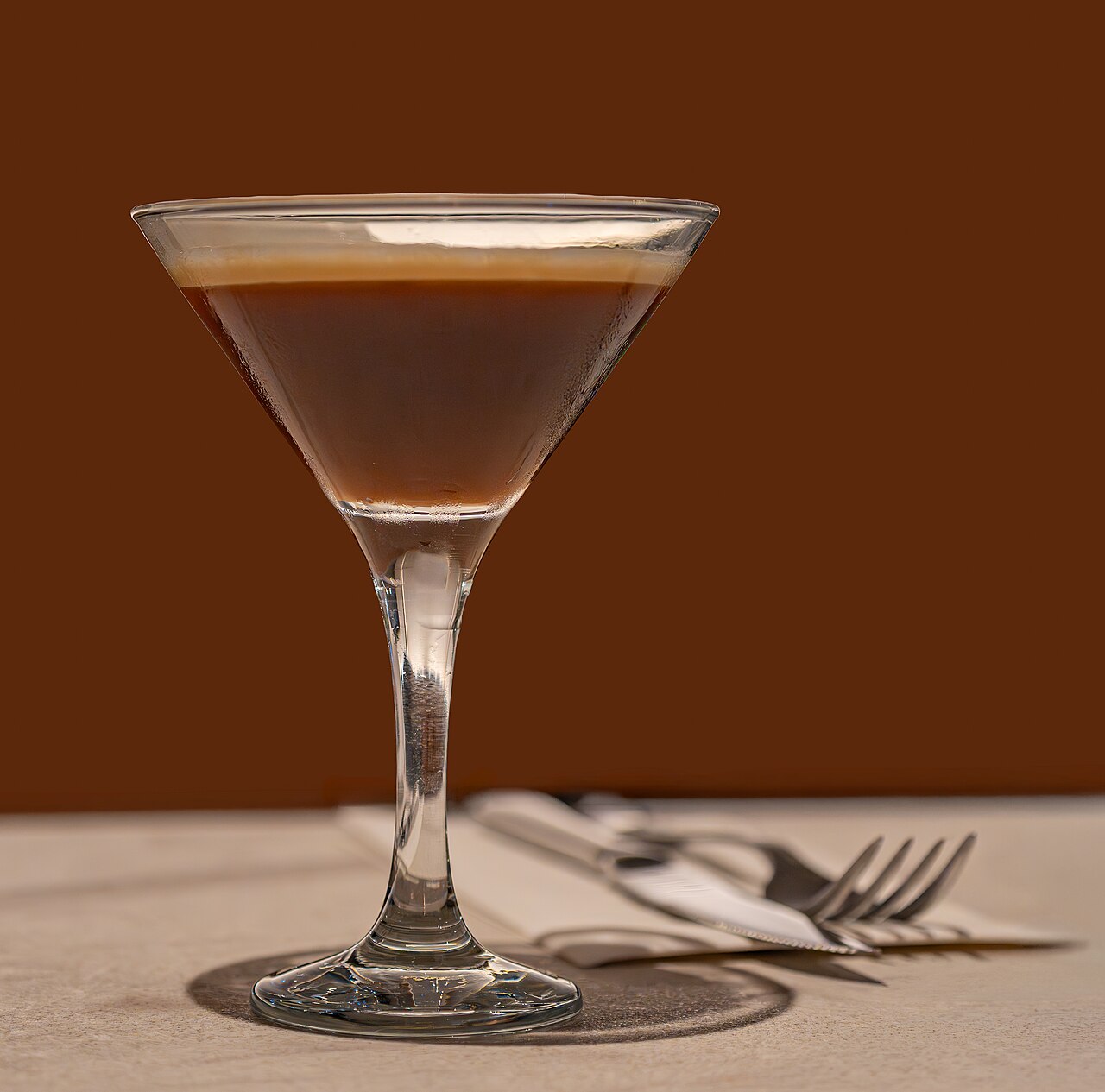 A dark coffee cocktail with a dense foam cap